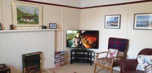 a living room with a tv on the wall at Tigh na Camus in Glenelg