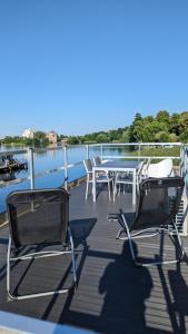 2 Stühle und ein Tisch auf einer Terrasse mit Wasser in der Unterkunft Waterview - Schwimmendes Ferienhaus auf dem Wasser mit Blick zur Havel, inkl Motorboot zur Nutzung in Fürstenberg-Havel