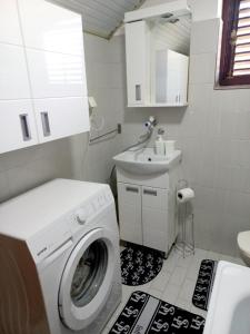 ein Badezimmer mit einer Waschmaschine und einem Waschbecken in der Unterkunft Apartman Alex 7 in Bajina Bašta