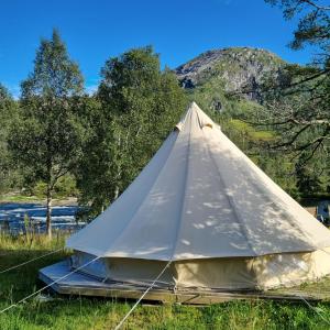ein weißes Zelt im Gras in der Nähe eines Flusses in der Unterkunft Flatheim Glamping in Viksdalen + 11 Fotos