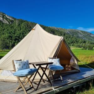 a tent with two chairs and a table on a deck at Flatheim Glamping in Viksdalen