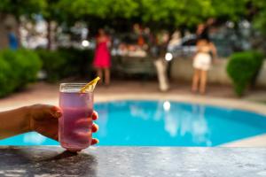 a hand holding a drink in front of a pool at -VİLLA Vildan- 12 KİŞİLİK ÖZEL HAVUZLU 6 ODALI VİLLA in Kemer