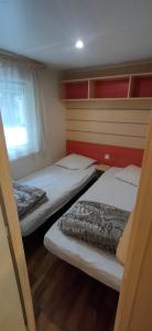 Mobil home 6-8 places en Camping 4etoiles Saint Cyprien في سان سيبريان: سريرين في غرفة صغيرة مع نافذة