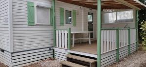 einen Außenblick auf ein kleines Haus mit einer Veranda in der Unterkunft Mobil home 6-8 places en Camping 4etoiles Saint Cyprien in Saint-Cyprien