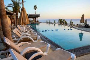 uma piscina com espreguiçadeiras e guarda-sóis em O Beach Hotel & Resort em Sowayma