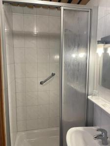 a shower with a glass door next to a sink at Hotel zum Markgrafen in Lüdenscheid