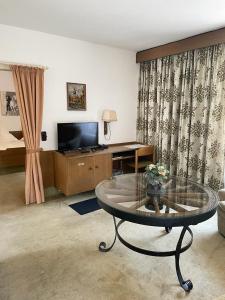 a living room with a glass table and a television at Hotel zum Markgrafen in Lüdenscheid