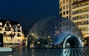 a glass dome building in a city at night at Suite 133 hotel studio in Knokke-Heist
