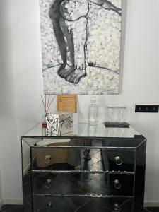 a black dresser with a painting on the wall at Hospedería 16 in Tarifa