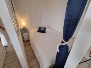 - une petite chambre avec un lit et un rideau bleu dans l'établissement Petite maison avec jardin face mer, à Agon-Coutainville