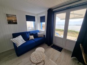 ein Wohnzimmer mit einem blauen Sofa und einem großen Fenster in der Unterkunft Petite maison avec jardin face mer in Agon Coutainville