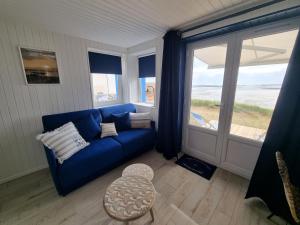 a living room with a blue couch and a large window at Petite maison avec jardin face mer in Agon Coutainville