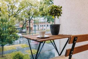 una mesa con una taza de café y una planta en una ventana en Luxury Smart Apartman JJ en Szeged