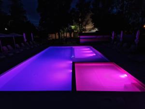 a swimming pool lit up with purple lights at night at Colors Holiday Hotel in Siófok