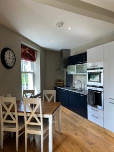 a kitchen with a table and chairs and a clock on the wall at Luxury Apartment - Great Location in Ecclesall