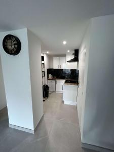uma cozinha branca com um relógio na parede em Appartement cap agde port 4 couchage em Cap d'Agde