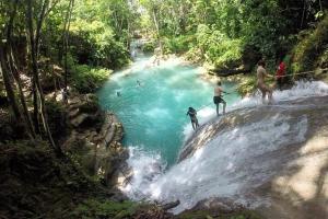 a group of people surfing on a waterfall in a river at Rio View Apartments in Ocho Rios