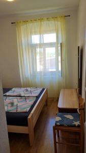 a bedroom with a bed and a window and a table at Apartman Mila in Belej