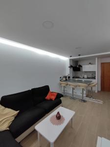 uma sala de estar com um sofá preto e uma mesa em Dúplex Casa Ana Apartaclub La Barrosa em Chiclana de la Frontera