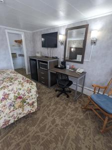 a hotel room with a desk and a bed and a mirror at Bennington Motor Inn in Bennington