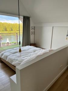 ein großes weißes Bett in einem Zimmer mit Fenster in der Unterkunft Ons Maashuisje in Maaseik