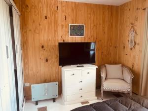 una sala de estar con TV en un armario y una silla en Rincón Natural Urbano en San Salvador de Jujuy