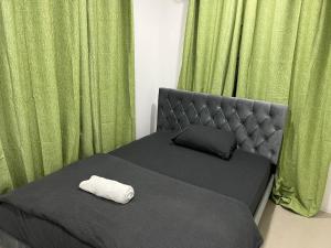 uma cama com cabeceira, uma almofada e cortinas verdes em Bula Homestay em Labasa