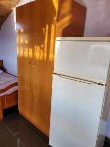 a kitchen with a white refrigerator and a wooden cabinet at Apartamente plazhi in Sarandë