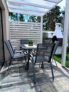 una mesa y sillas en un patio con una pérgola blanca en Lawendowe Domki i Apartamenty w Pobierowie, en Pobierowo