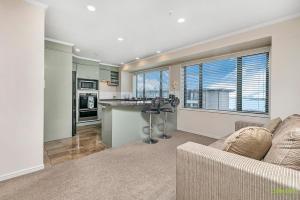 a living room with a couch and a kitchen at QV Stays Front Stage City Lights in Auckland
