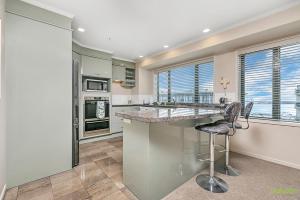 a kitchen with a counter and two stools at QV Stays Front Stage City Lights in Auckland