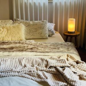 una manta blanca sobre una cama con una vela en die perfekte Auszeit, en Illingen