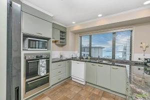 a kitchen with white cabinets and a large window at QV Stays Front Stage City Lights in Auckland +18 photos