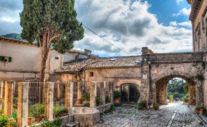 un antico edificio in pietra con arco e albero di Valldemosa Sleep & Hike a Valldemossa