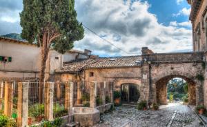 an old stone building with an arch and a tree at Valldemosa Sleep & Hike in Valldemossa
