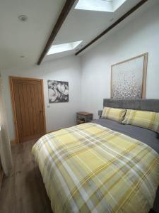 um quarto com uma cama com um cobertor xadrez amarelo em Belle Vue Cottage sleeps 2 one dog by prior permission em Barnard Castle