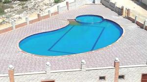 une grande piscine bleue au-dessus d'un bâtiment dans l'établissement Aida, à El Alamein