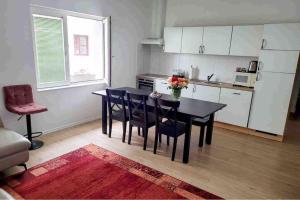 una cocina con mesa negra y sillas y una cocina con armarios blancos. en 70qm Apartment für sie und ihre Familie, 