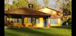 une maison jaune avec un toit brun dans l'établissement Casa de Campo Finca el Paraiso, à Zipacón