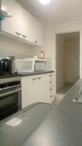 cocina con armarios blancos y fogones en Aqua Suite en Gillingham