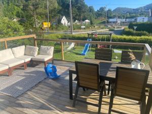 a deck with a table and chairs and a playground at Hus med hage og terasse, ideelt for familier in Lyngdal