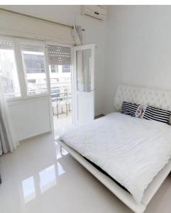 een witte slaapkamer met een wit bed en een raam bij Big apt near sea best position tlv in Tel Aviv
