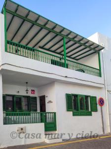 a white building with green shutters and a balcony at Casa mar y cielo in Playa Blanca