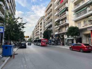 um autocarro vermelho a descer uma rua da cidade com carros em Nick's Place em Tessalônica