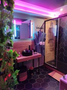 La salle de bains est pourvue d'un lavabo et d'une douche avec des lumières violettes. dans l'établissement Cocon d'Evasion**** SPA PRIVATIF et ciels étoilés, au Havre