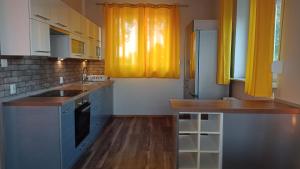 a kitchen with blue cabinets and yellow curtains at Apartament Słoneczny in Poznań