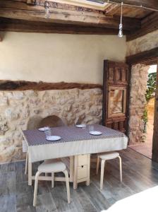 una mesa y sillas en una habitación con una pared de piedra en Casa rural El Rincón de las Estrellas en Sigüenza