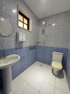 uma casa de banho em azulejos azuis com um WC e um lavatório em La Remonta Residence em Ipiabas