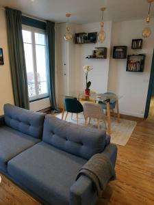 een woonkamer met een blauwe bank en een tafel bij Superbe appartement moderne et lumineux à Puteaux! in Puteaux