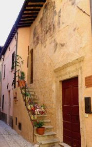 a stone building with stairs and a red door at Twins' Historical Apartment in Trevi